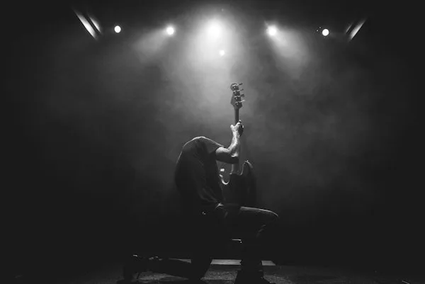 Guitarist under a single spotlight, black and white