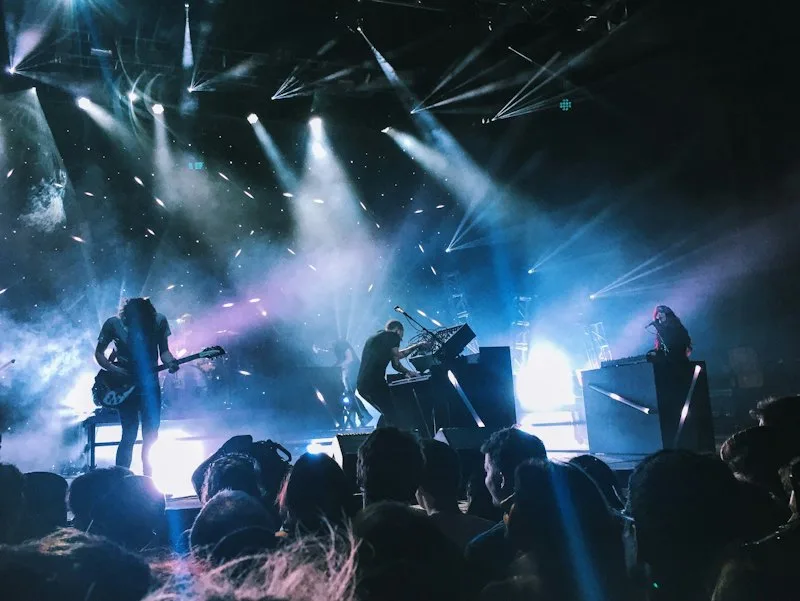 Band on a stage lit with blue and purple beams over the crowd